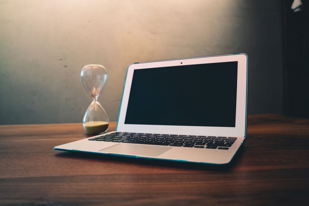 Computador lento: notebook aberto ao lado de uma ampulheta
