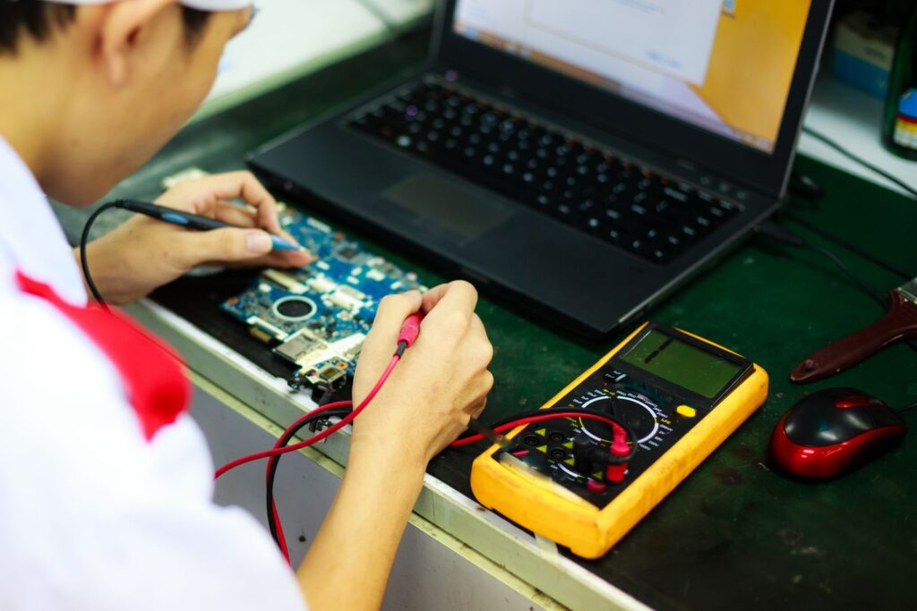 Placa-mãe do notebook sendo medida com multímetro durante o diagnóstico