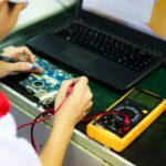 Placa-mãe do notebook sendo medida com multímetro durante o diagnóstico